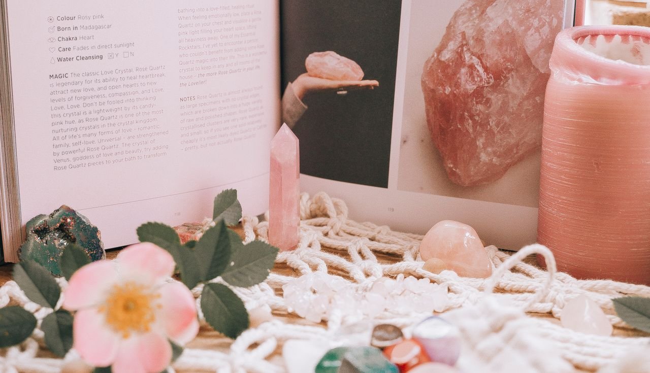 A calming composition featuring crystals, a candle, and a book open to a mystical page.